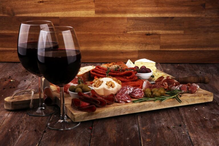 Cutting board with prosciutto, salami, cheese,bread and olives on dark wooden background